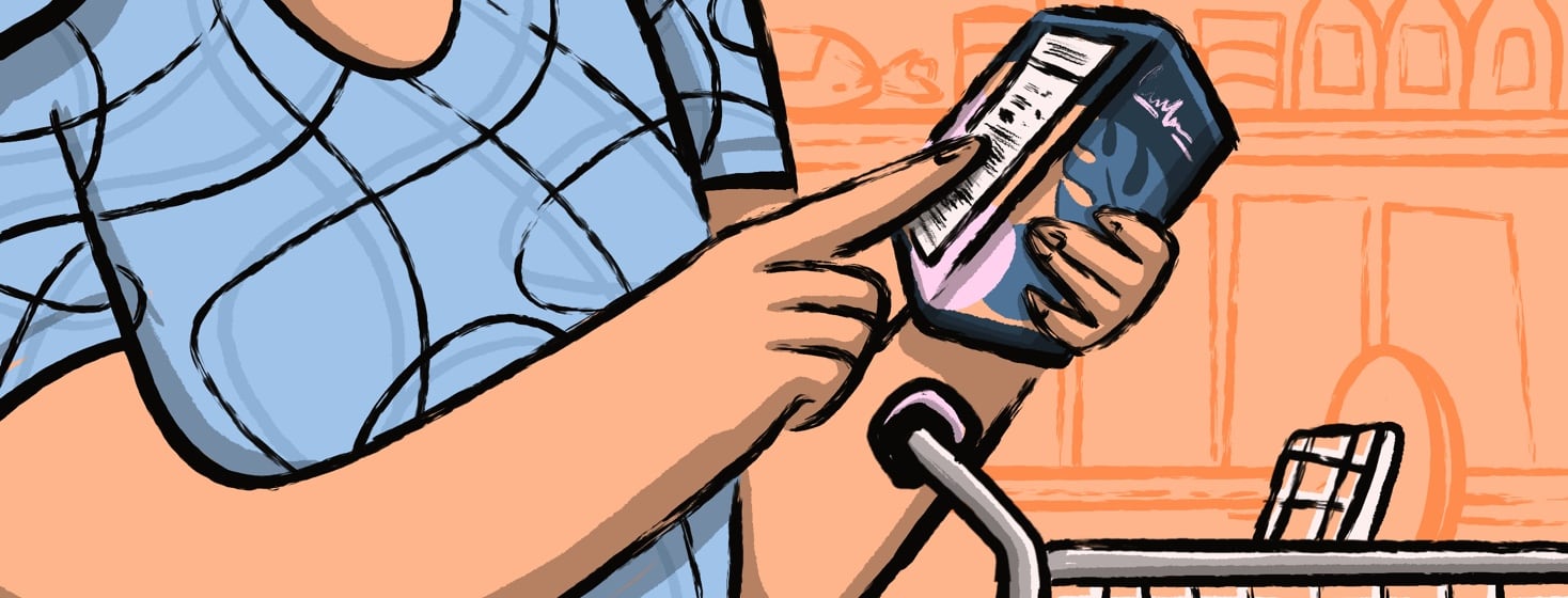 Person reading nutrition label while shopping at a grocery store with a shopping cart